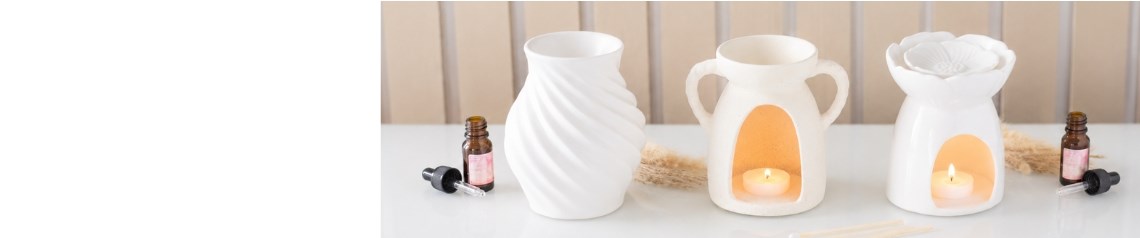 Matte white ceramic oil burners and wax melt warmers with spiritual designs including mandalas, angel wings and tree of life motifs. Elegant wholesale home fragrance accessories for calm and relaxing interiors. No minimum order, ships worldwide.