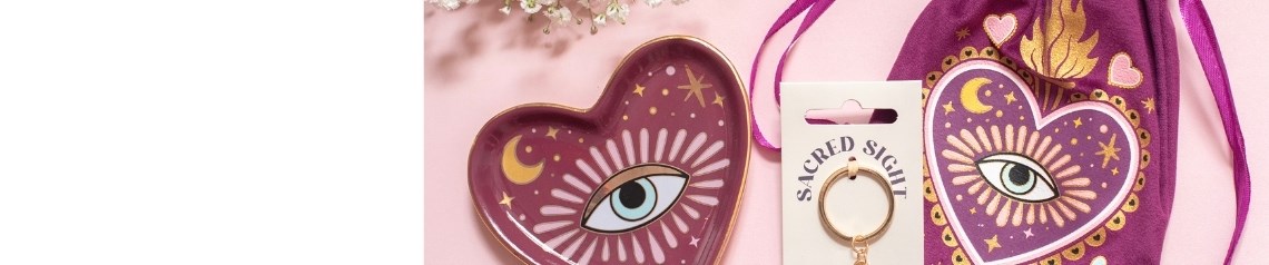 Coleção «Sacred Sight» de artigos para o lar e presentes em tons de ameixa e rosa, vendidos por grosso, incluindo cerâmicas, artigos para velas, vasos, capachos e acessórios com motivos de corações sagrados, olhos que tudo vêem, luas e estrelas.