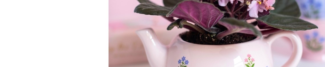 Tea-time-lahjakokoelma, jossa on pastellinpunaisia ja lila-värisiä mukeja, maljakoita ja öljylamppuja, joissa on hienostuneita kukkakuvioita ja calico-kissakuvioita.